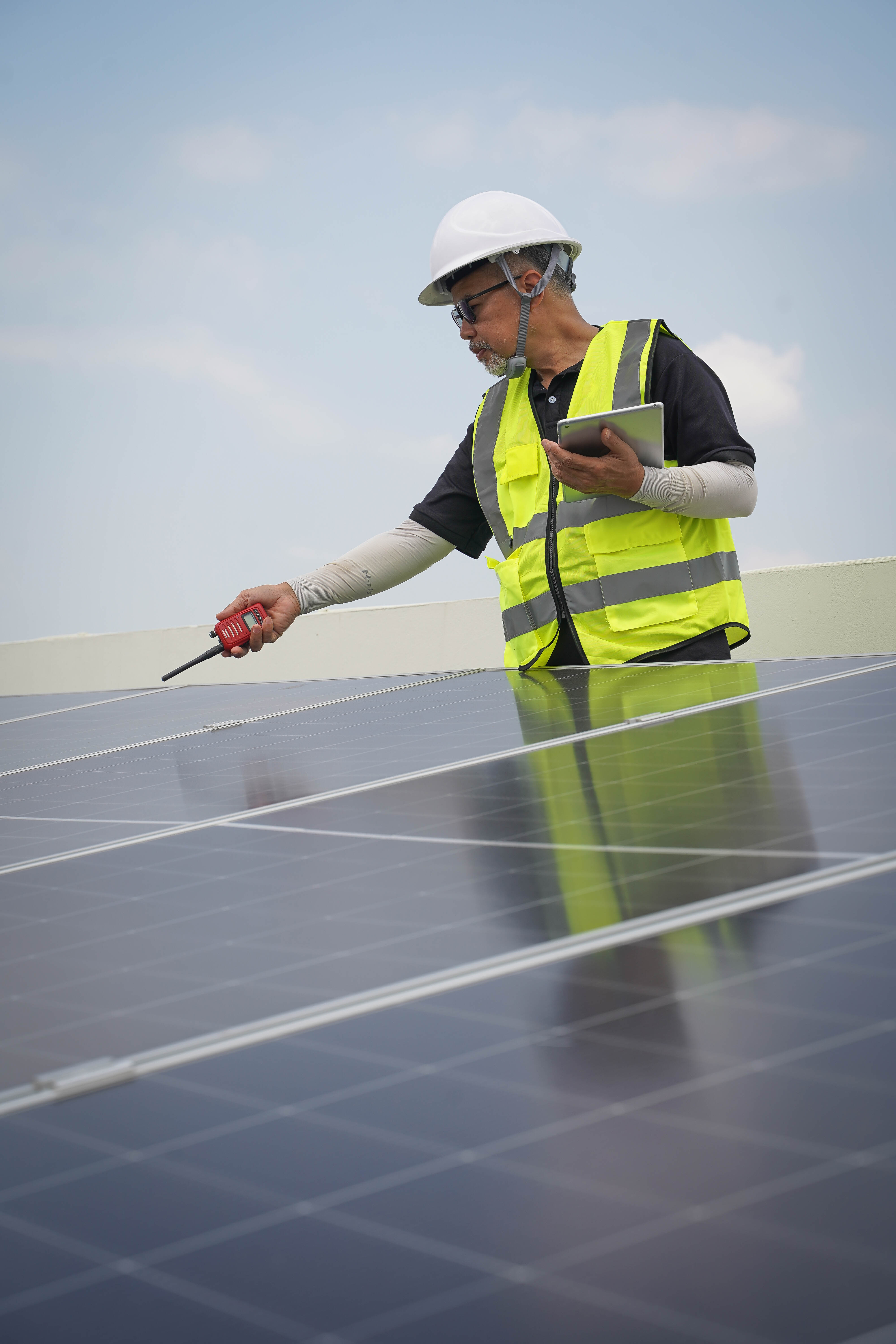 Professional engineer communicating via radio and monitoring solar panel efficiency through a digital tablet. Smart energy management and technology.