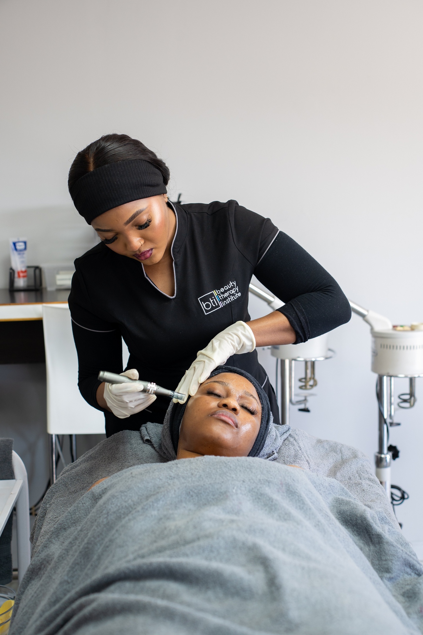 Close-up of a brush applying a facial mask to a reclining patient's cheek.